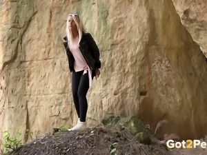 Straight blond haired cutie leans over the rock and pees right away